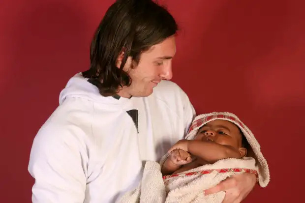 Fußballstar Lionel Messi hält das neugeborene Baby Lamine Yamal in ein Handtuch gewickelt im Arm